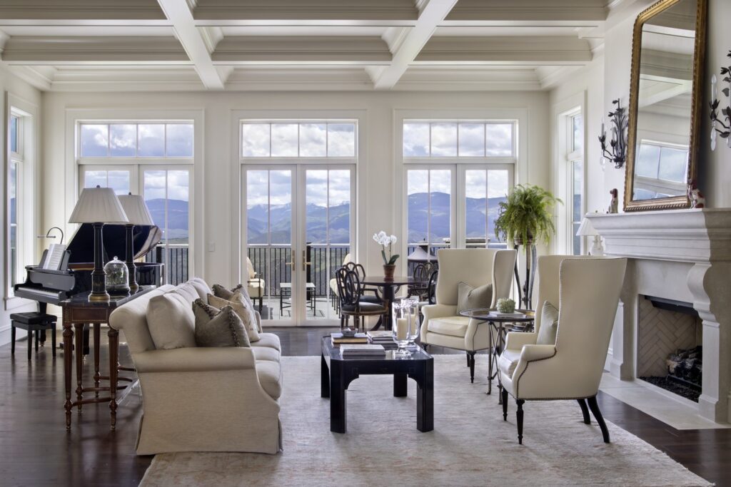 Elegant living room with mountain views, featuring coffered ceilings, grand piano, and cozy seating