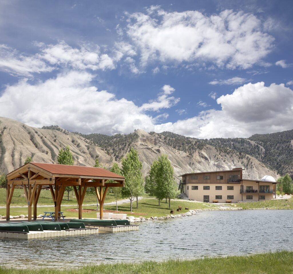 Beautiful ranch with a pavilion by the lake, set in scenic mountains under a bright, expansive sky