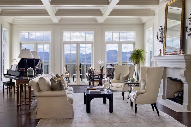 Elegant living room with mountain views, featuring a grand piano, large windows, and seating