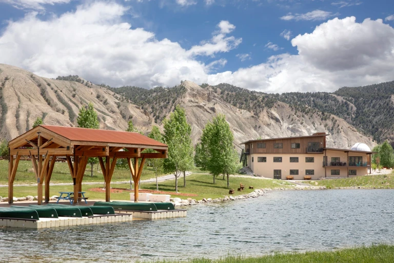 Beautiful ranch with a pavilion by the lake, set against scenic mountains under a bright sky